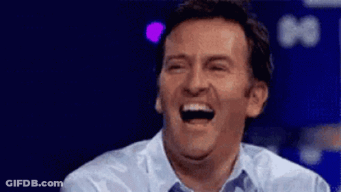 A Man Is Laughing With His Mouth Open While Wearing A Blue Shirt . GIF