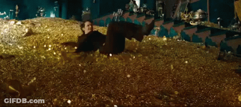 A Man Is Laying Down In A Pile Of Gold Coins . GIF
