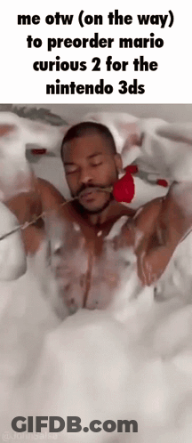 A Man Is Laying In A Bathtub Holding A Rose In His Mouth . GIF