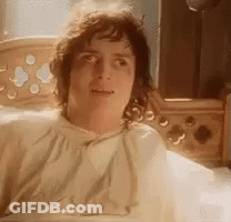 A Man Is Laying In A Bed With A Blanket On His Head And Looking At The Camera . GIF