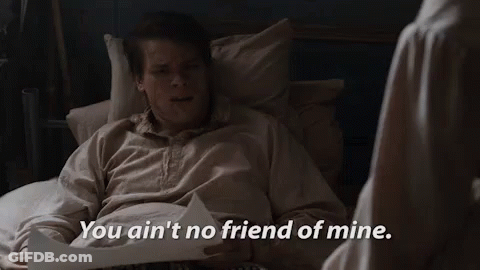 A Man Is Laying In A Bed With A Piece Of Paper And A Woman Is Standing Next To Him . GIF