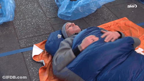 A Man Is Laying In A Blue Sleeping Bag With The Letters Sny On The Bottom Of The Image GIF