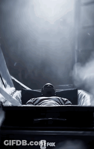A Man Is Laying In A Coffin With A Fox Logo On The Bottom GIF
