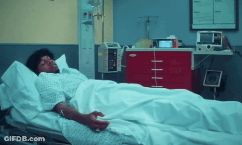 A Man Is Laying In A Hospital Bed Next To A Red Cabinet That Says ' Smith & Nephew ' On It GIF