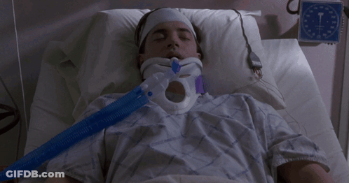 A Man Is Laying In A Hospital Bed With A Neck Brace GIF