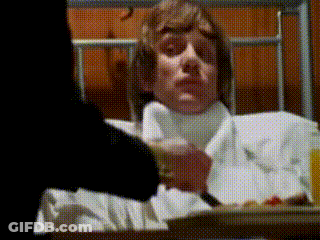 A Man Is Laying In A Hospital Bed With A Tray Of Food GIF