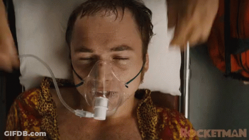 A Man Is Laying In A Hospital Bed With An Oxygen Mask On His Face .. GIF