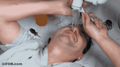 A Man Is Laying In A Sink With His Eyes Closed GIF