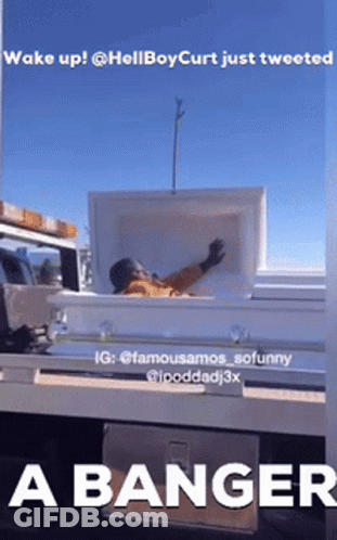 A Man Is Laying In A White Coffin On The Back Of A Truck GIF