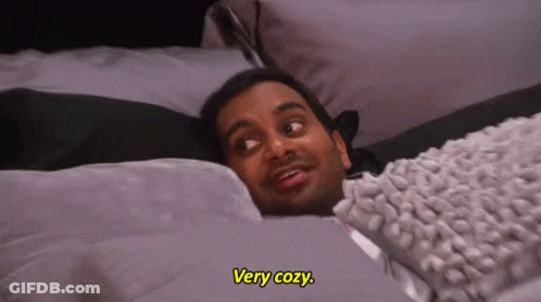 A Man Is Laying In Bed With A Blanket And A Pillow . GIF