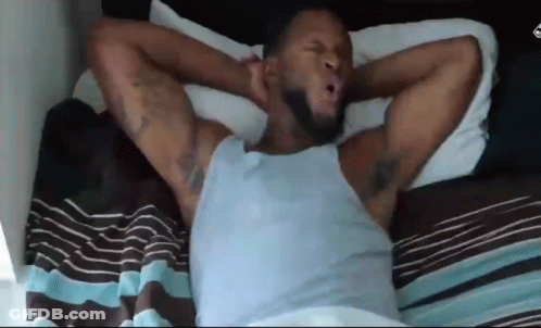 A Man Is Laying In Bed With His Arms Outstretched . GIF