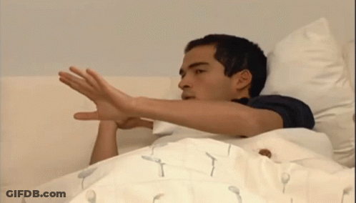 A Man Is Laying In Bed With His Hand Out GIF