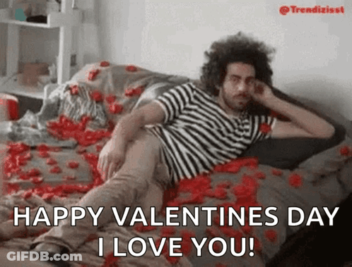 A Man Is Laying On A Bed Covered In Rose Petals And Says Happy Valentines Day I Love You . GIF