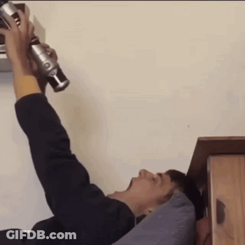 A Man Is Laying On A Bed Holding A Green Lightsaber GIF