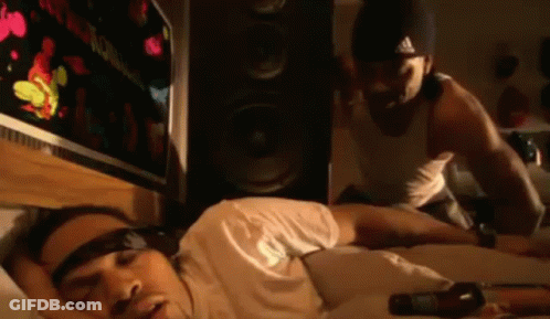 A Man Is Laying On A Bed With A Bottle Of Beer In Front Of Him . GIF