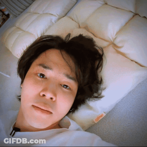 A Man Is Laying On A Bed With A Pillow That Says ' A ' On It GIF