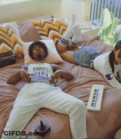A Man Is Laying On A Bed With A Shirt That Says Puddle On It GIF