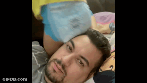 A Man Is Laying On A Bed With A Woman 'S Butt On His Head . GIF