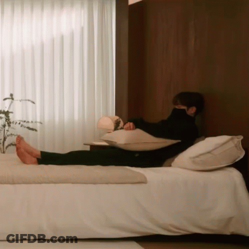 A Man Is Laying On A Bed With His Feet Up GIF