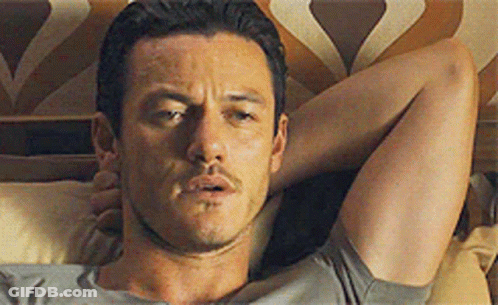 A Man Is Laying On A Bed With His Head On A Pillow . GIF