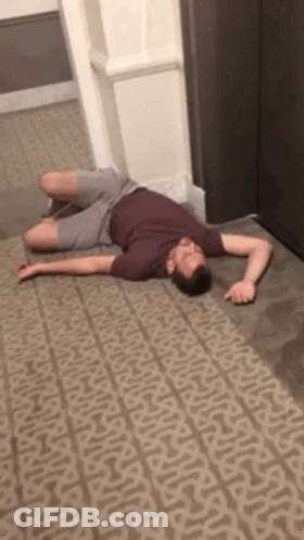 A Man Is Laying On A Carpet In A Hallway . GIF