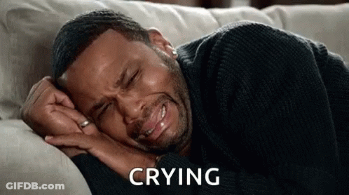 A Man Is Laying On A Couch Crying With His Eyes Closed . GIF