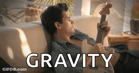 A Man Is Laying On A Couch Playing A Guitar And The Word Gravity Is Above Him . GIF