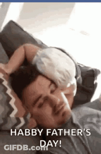 A Man Is Laying On A Couch With A Baby Sleeping On His Head . GIF