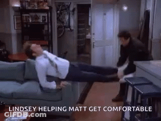 A Man Is Laying On A Couch With A Woman Standing Next To Him And The Words Lindsey Helping Matt Get Comfortable Above Hi GIF
