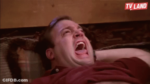 A Man Is Laying On A Couch With His Mouth Open And Laughing . GIF