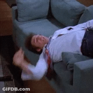 A Man Is Laying On A Couch With His Tie Hanging Off Of Him . GIF