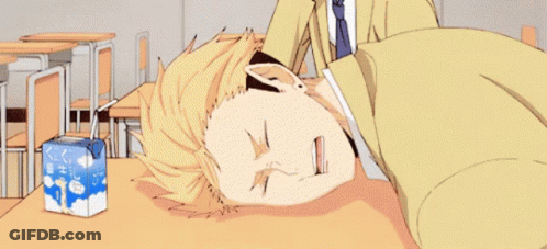 A Man Is Laying On A Desk In A Classroom Next To A Box Of Milk . GIF