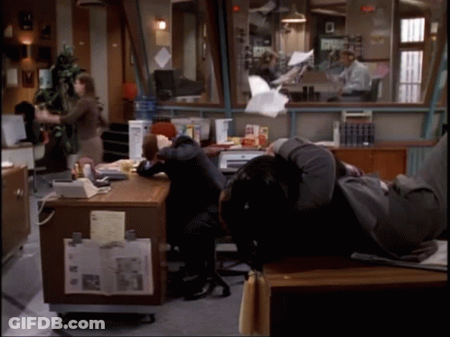 A Man Is Laying On A Desk In An Office GIF