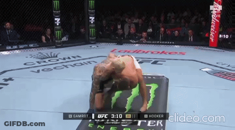 A Man Is Laying On A Mat In A Boxing Ring With A Budweiser Ad In The Background GIF