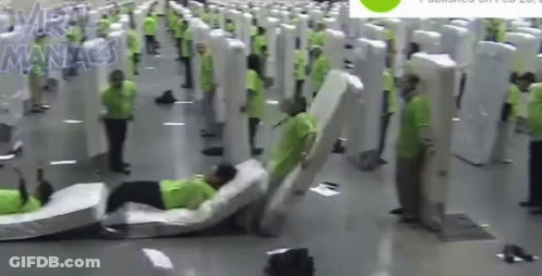 A Man Is Laying On A Mattress In A Room With A Lot Of Mattresses . GIF