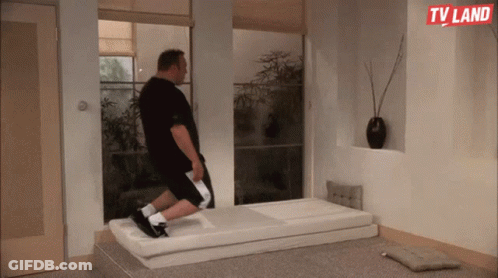 A Man Is Laying On A Mattress In A Room With A Tv Land Logo On The Wall GIF