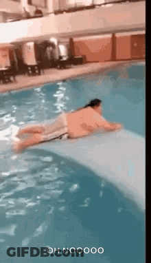 A Man Is Laying On A Raft In A Pool . GIF