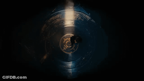 A Man Is Laying On A Record In The Dark . GIF