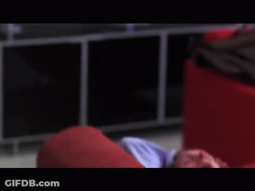 A Man Is Laying On A Red Couch With His Eyes Closed GIF