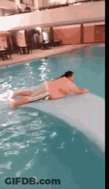 A Man Is Laying On A Slide In A Swimming Pool GIF