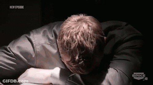 A Man Is Laying On A Table With His Head On His Hands . GIF