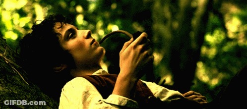 A Man Is Laying On A Tree Branch Holding A Pipe In His Hand GIF