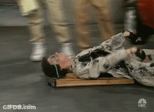 A Man Is Laying On A Wooden Plank With A Nbc Logo On The Bottom GIF
