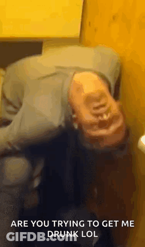 A Man Is Laying On His Back In A Bathroom With The Words `` Are You Trying To Get Me Drunk Lol '' Above Him . GIF