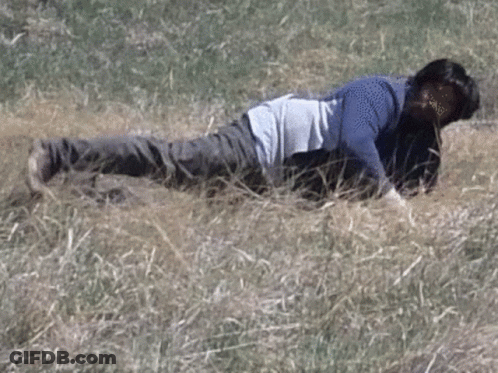 A Man Is Laying On His Back In The Grass . GIF