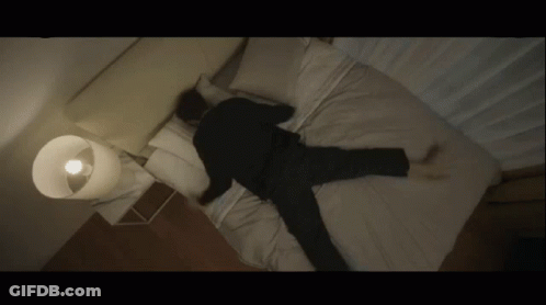 A Man Is Laying On His Back On A Bed With His Legs Crossed GIF