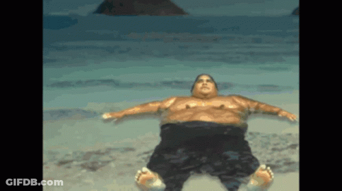 A Man Is Laying On His Back On The Beach GIF