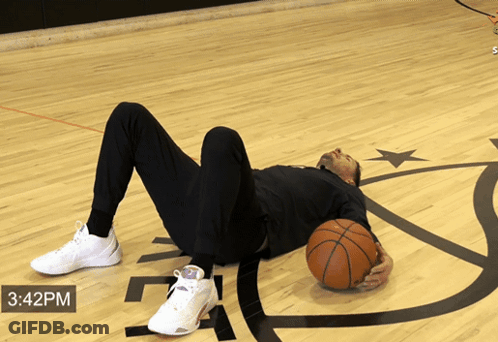 A Man Is Laying On The Floor Holding A Basketball With The Time Of 3:42 Pm GIF