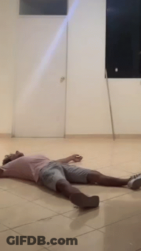 A Man Is Laying On The Floor In A Room With A Mop . GIF