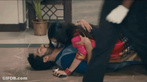 A Man Is Laying On The Floor With A Woman Holding Him . GIF
